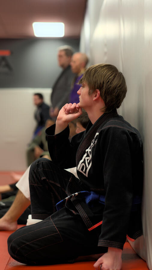 Jiu Jitsu students sitting against wall.